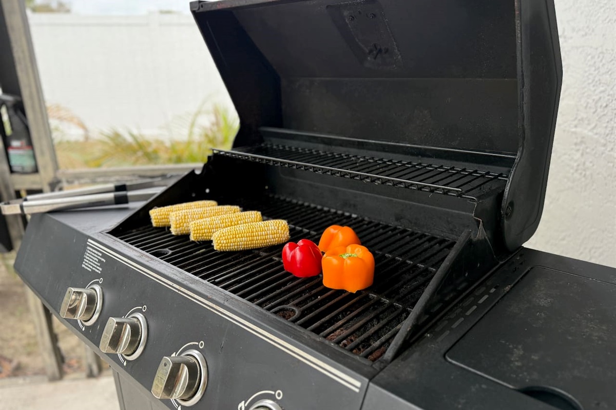 Gas grill sitting on the back patio near the pool area ready to grill an amazing lunch