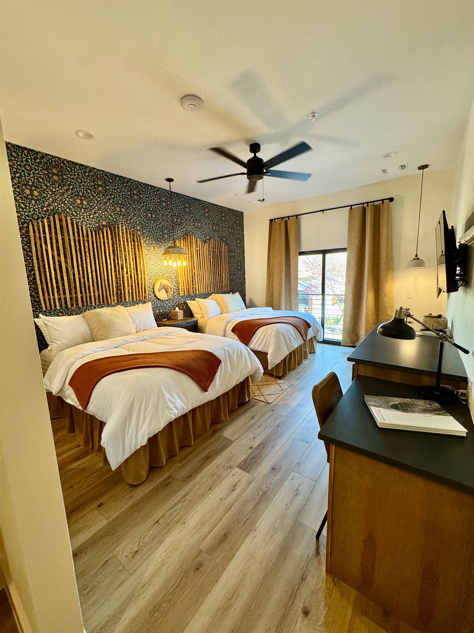 Corral Suite at Gaines Ranch on the Square — double queen beds in premium Comphy linens against a custom modern Western feature wall. Small desk, storage and sitting area for comfortable stay.
