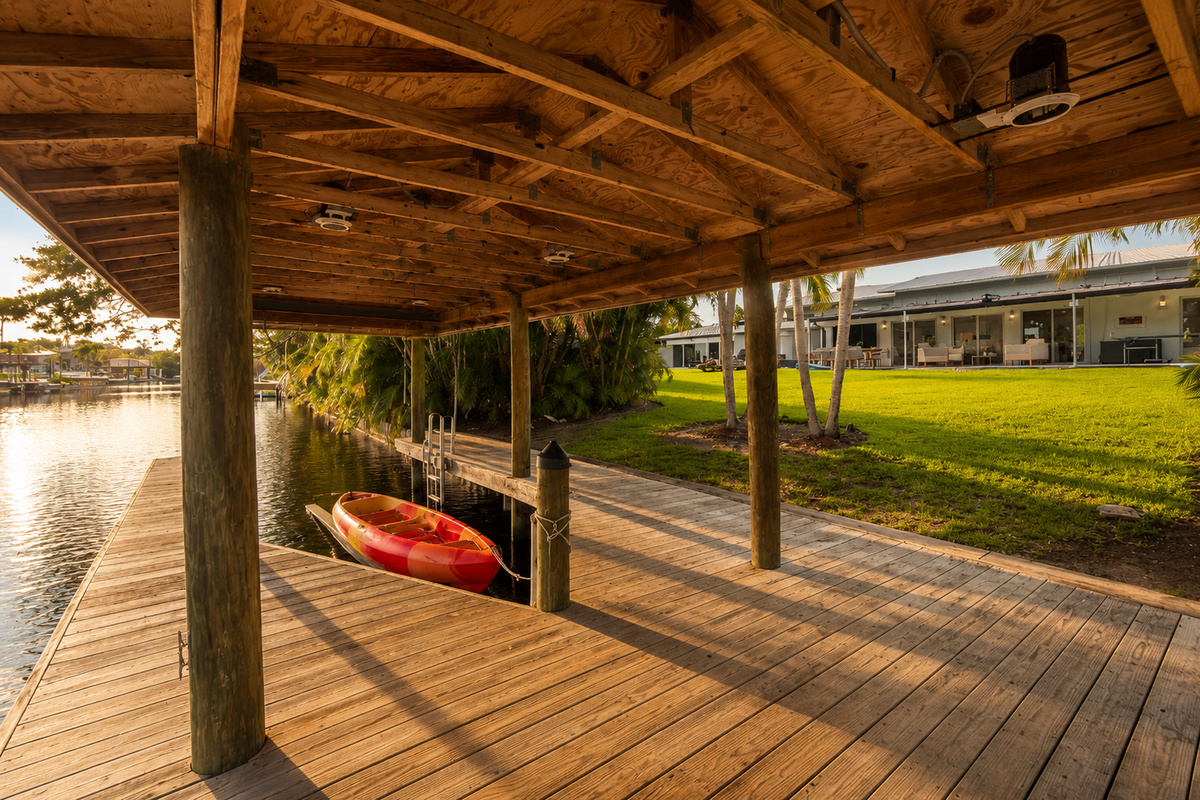 The covered dock and kayak storage add a waterfront feel to your stay, with the canal just beyond the backyard.