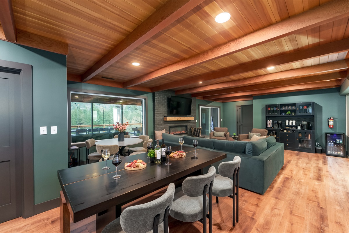 Expansive living and dining space with generous seating, mountain views, and a stylish fireplace, offering the perfect hub for meals, movies, and reconnecting with your group.