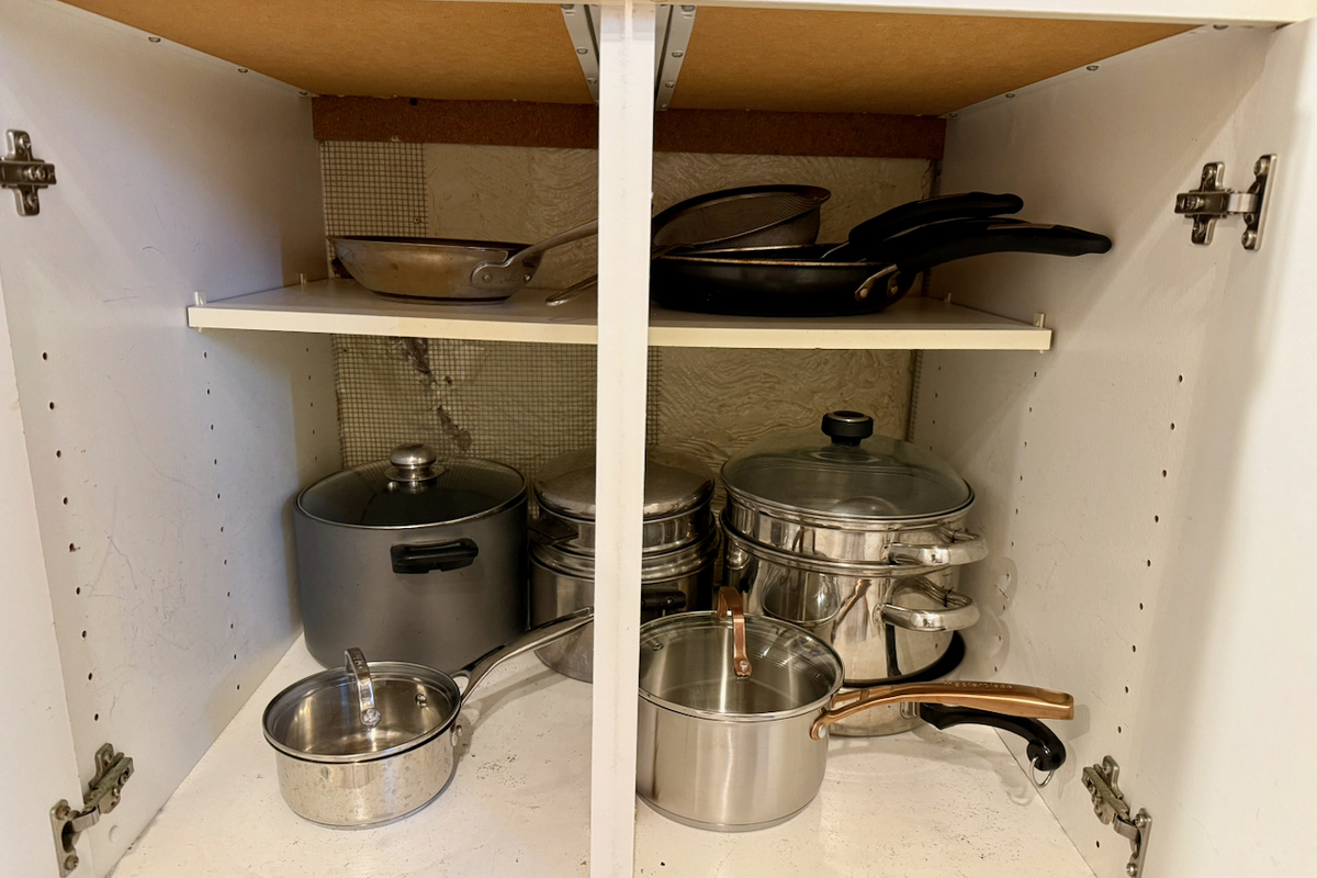 The kitchen cabinets contain a variety of stainless steel and non-stick pots and pans.