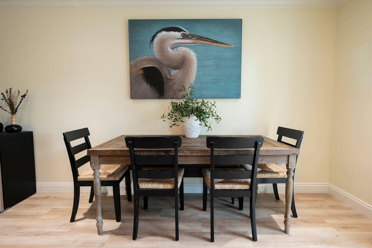 Rustic dining charm: Heron art, cozy table, and stylish black chairs.
