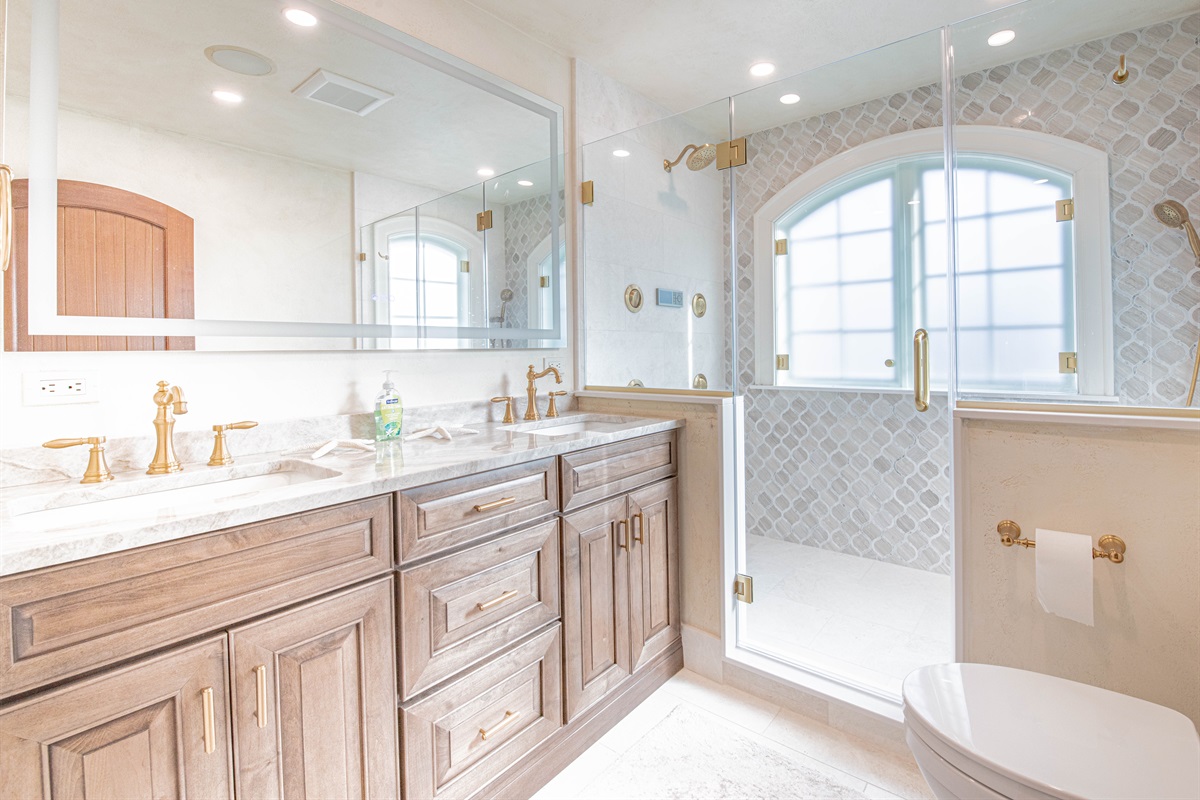 King ensuite bath with double vanity sinks and stunning tiled shower