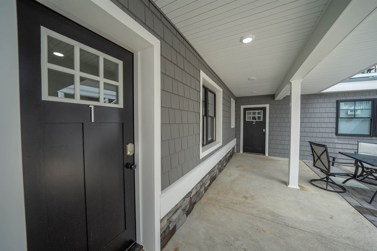 Covered entry porch with private access, featuring a clean, sheltered walkway and seating area. A practical outdoor space for arrivals, departures, or quiet moments outside, offering protection from the elements and a calm transition into the home.