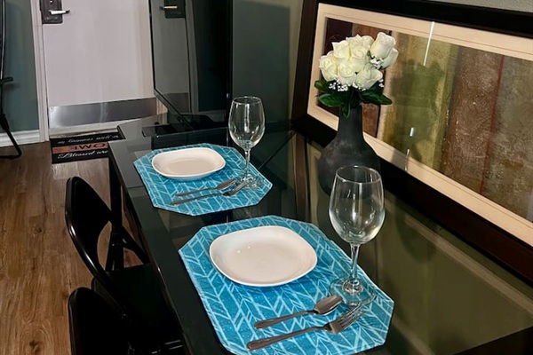 Dining corner with a small table, full-size fridge, TV, and an easy spot for meals or work.

