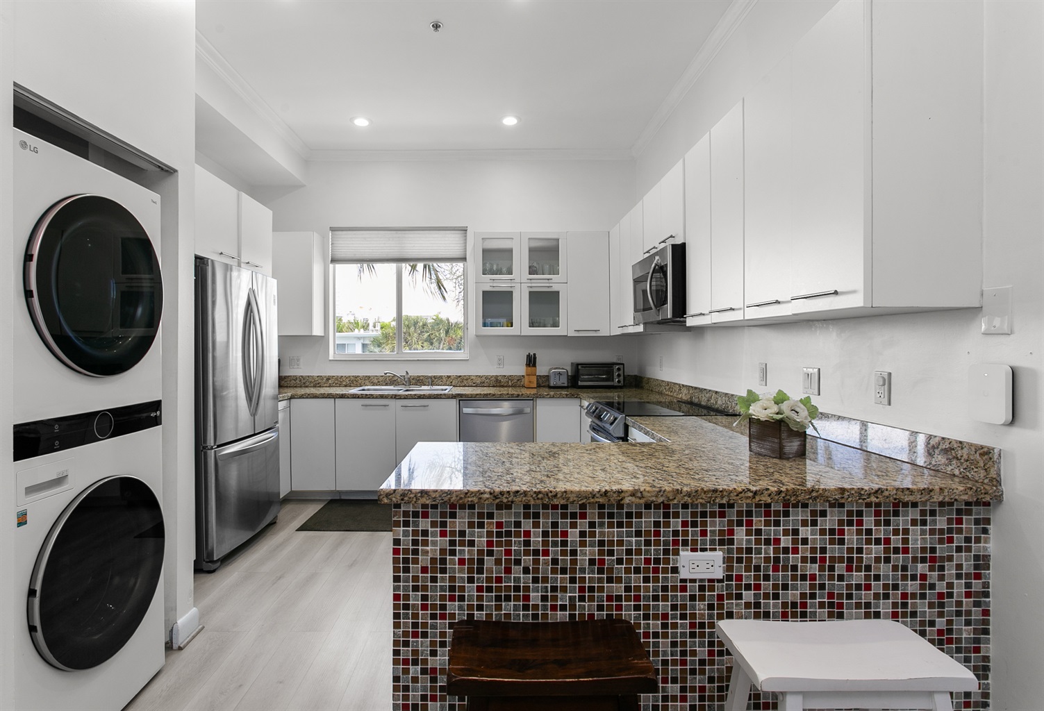 Induction range, French door fridge with bottom freezer, and breakfast counter. LG laundry tower right next to it.