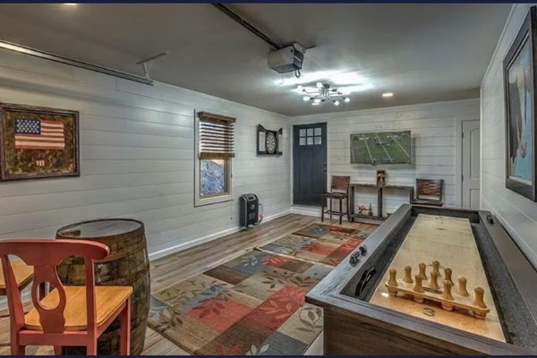 Game room with shuffleboard, foosball, darts, TV, and cozy cabin charm.