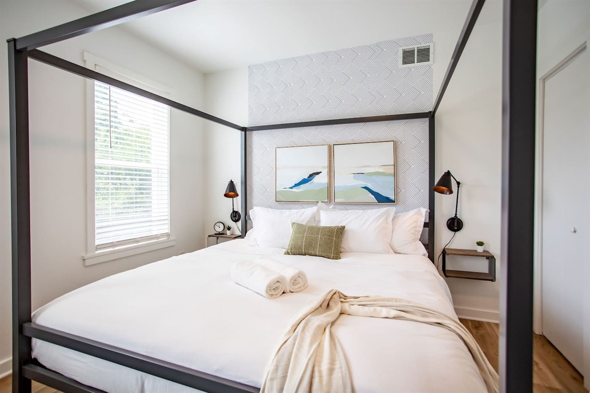 Cozy bed positioned next to a window, with a bright white interior that creates a serene, airy atmosphere for a peaceful night's sleep.