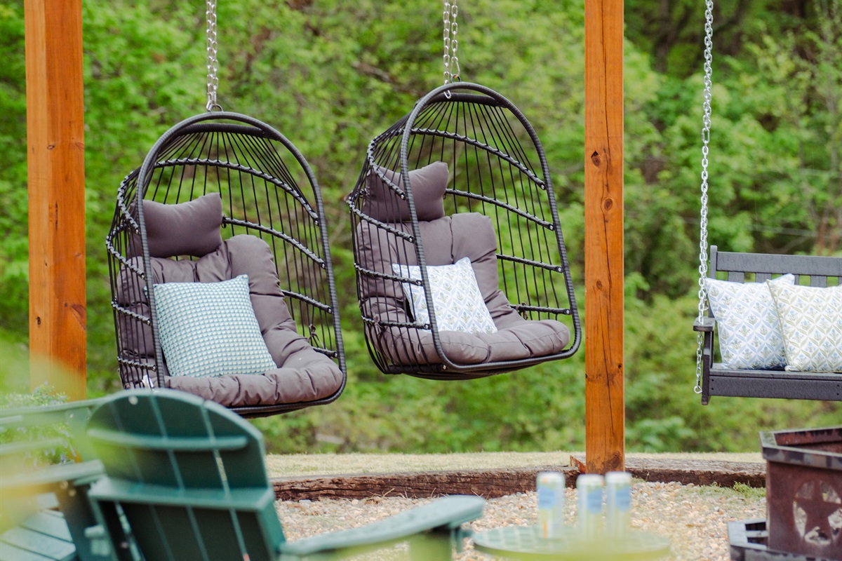 Unwind by the firepit in hanging egg chairs beneath a canopy of twinkling lights