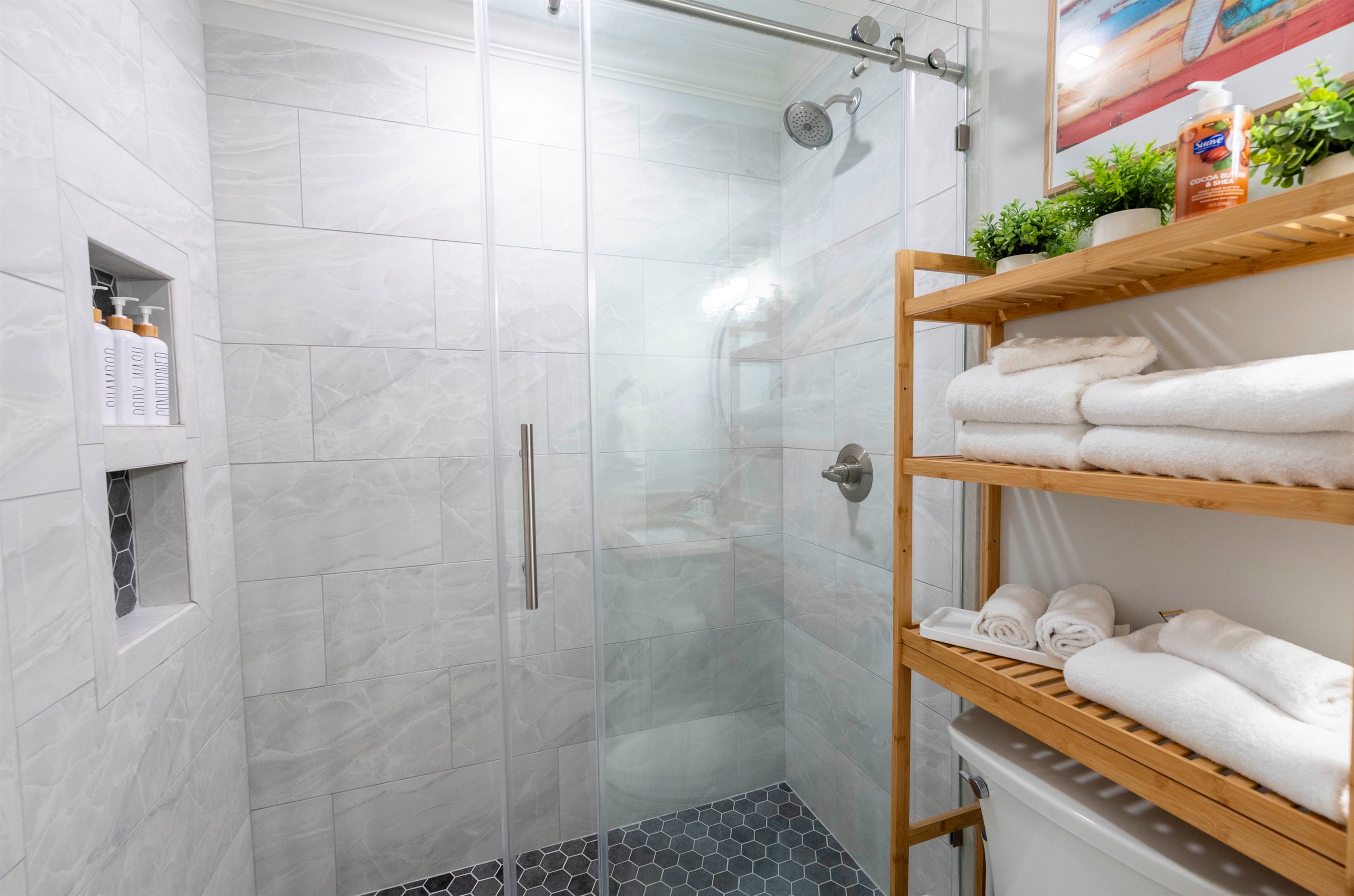 Modern bathroom with glass shower, wooden shelves, and fresh, cozy vibes!