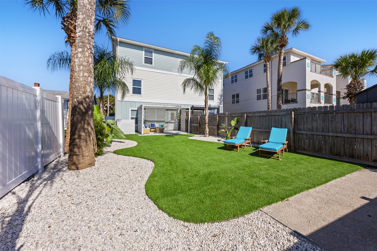 Spacious private backyard with lounge chairs and palm trees