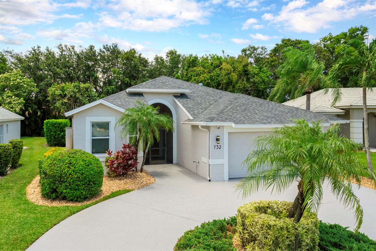 A wide, welcoming driveway framed by lush Florida landscaping