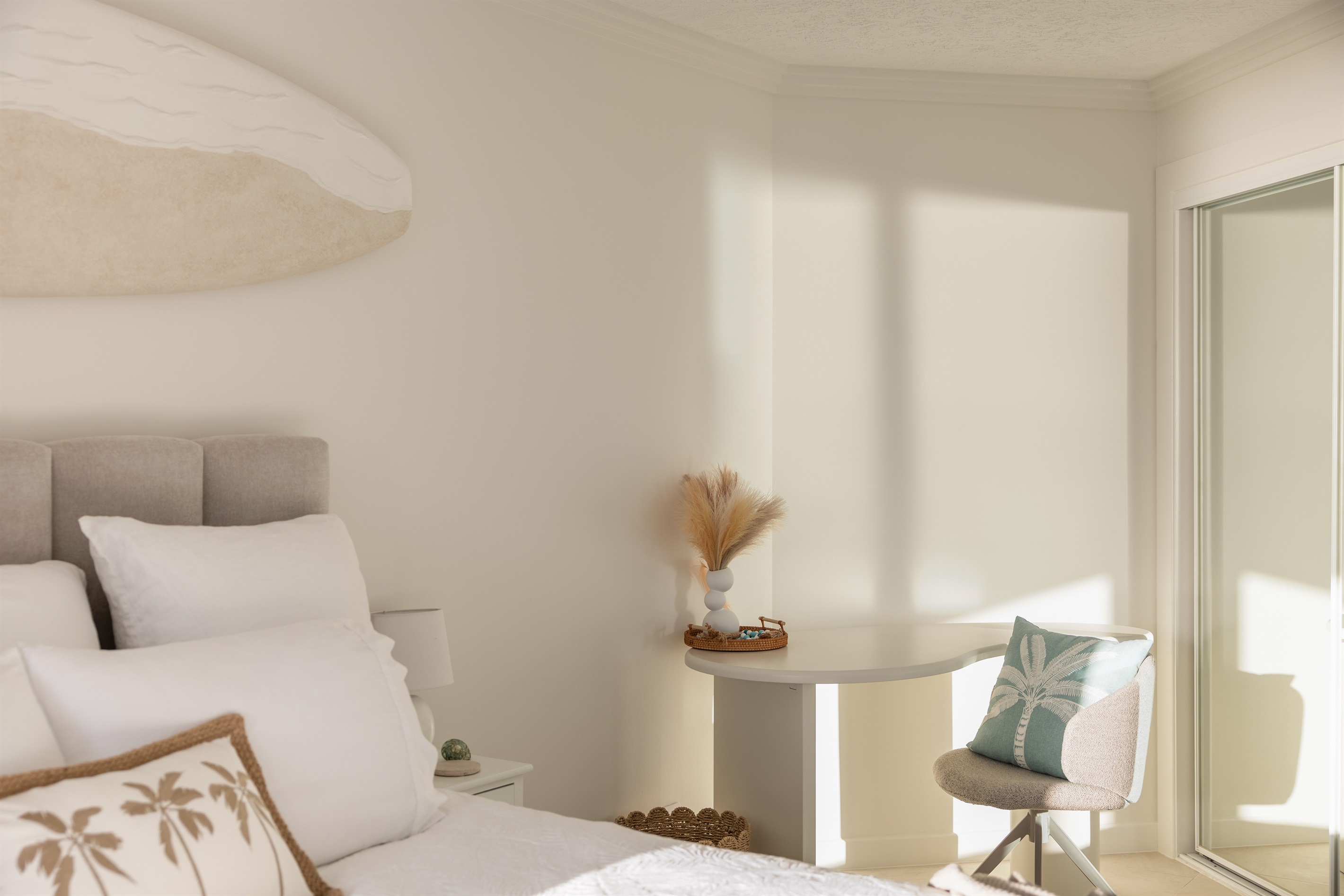 Relaxing coastal bedroom with workspace and plush bedding.