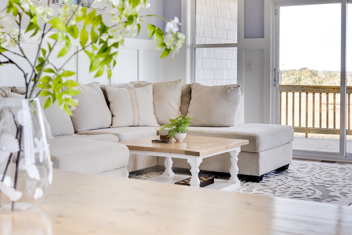 From the sofa, enjoy peaceful views toward the deck, creating a seamless indoor-outdoor feel that defines Surf City Sunsets