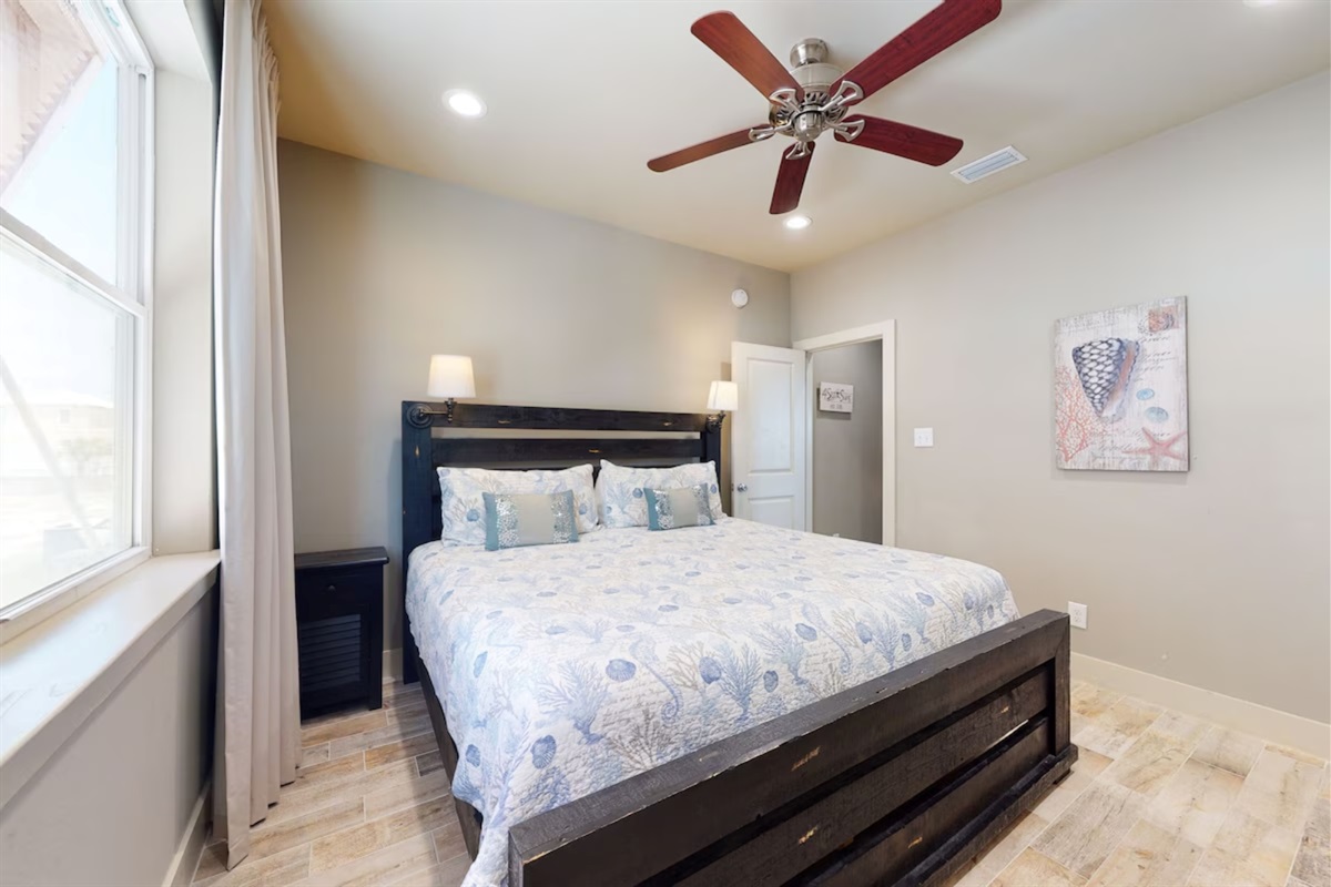Main level bedroom with king bed, ceiling fan, TV and en-suite bathroom  