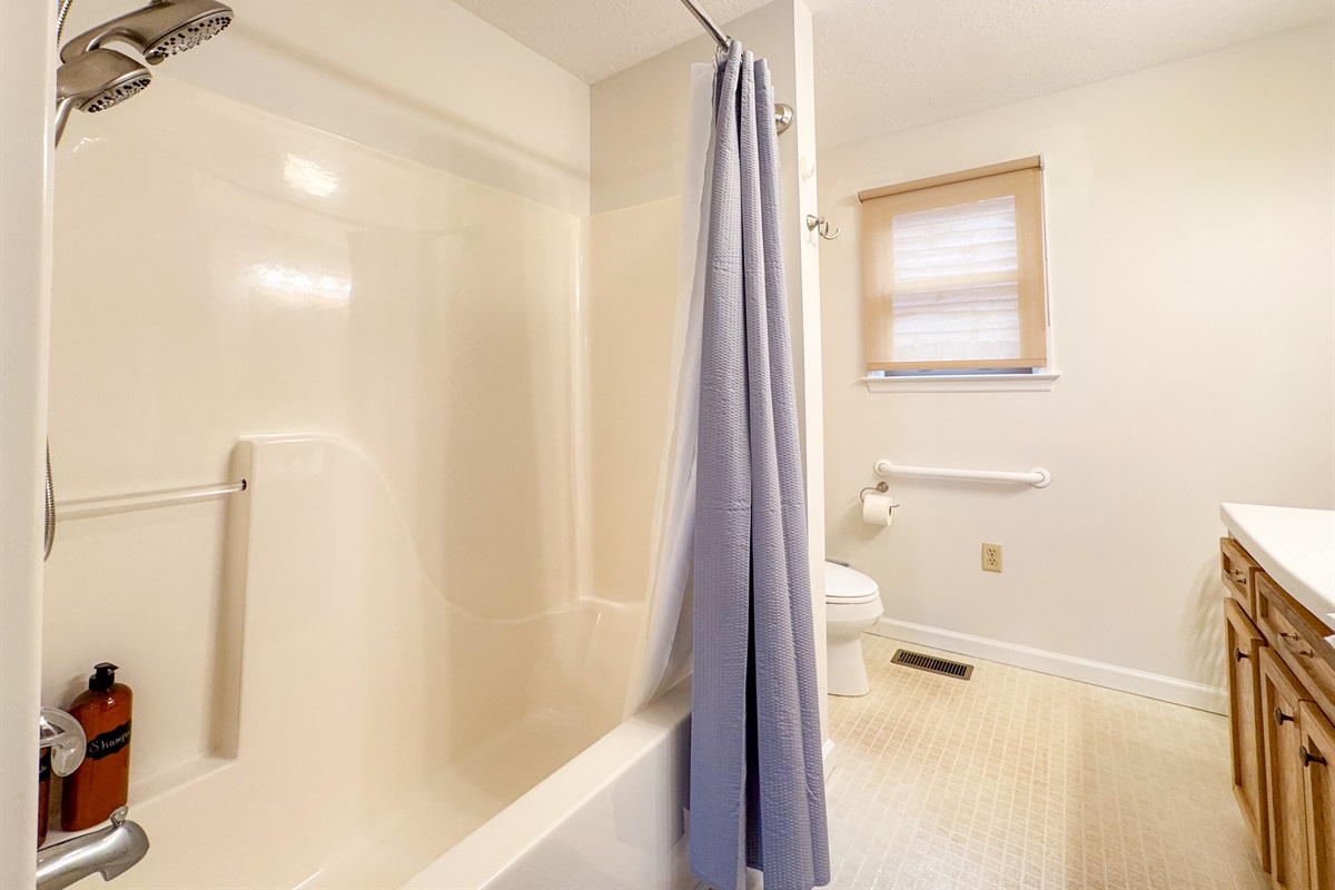 The ensuite bathroom features a tub/shower combination, toilet, vanity, grab bars, and a separate stall shower with low clearance! A rare treat!