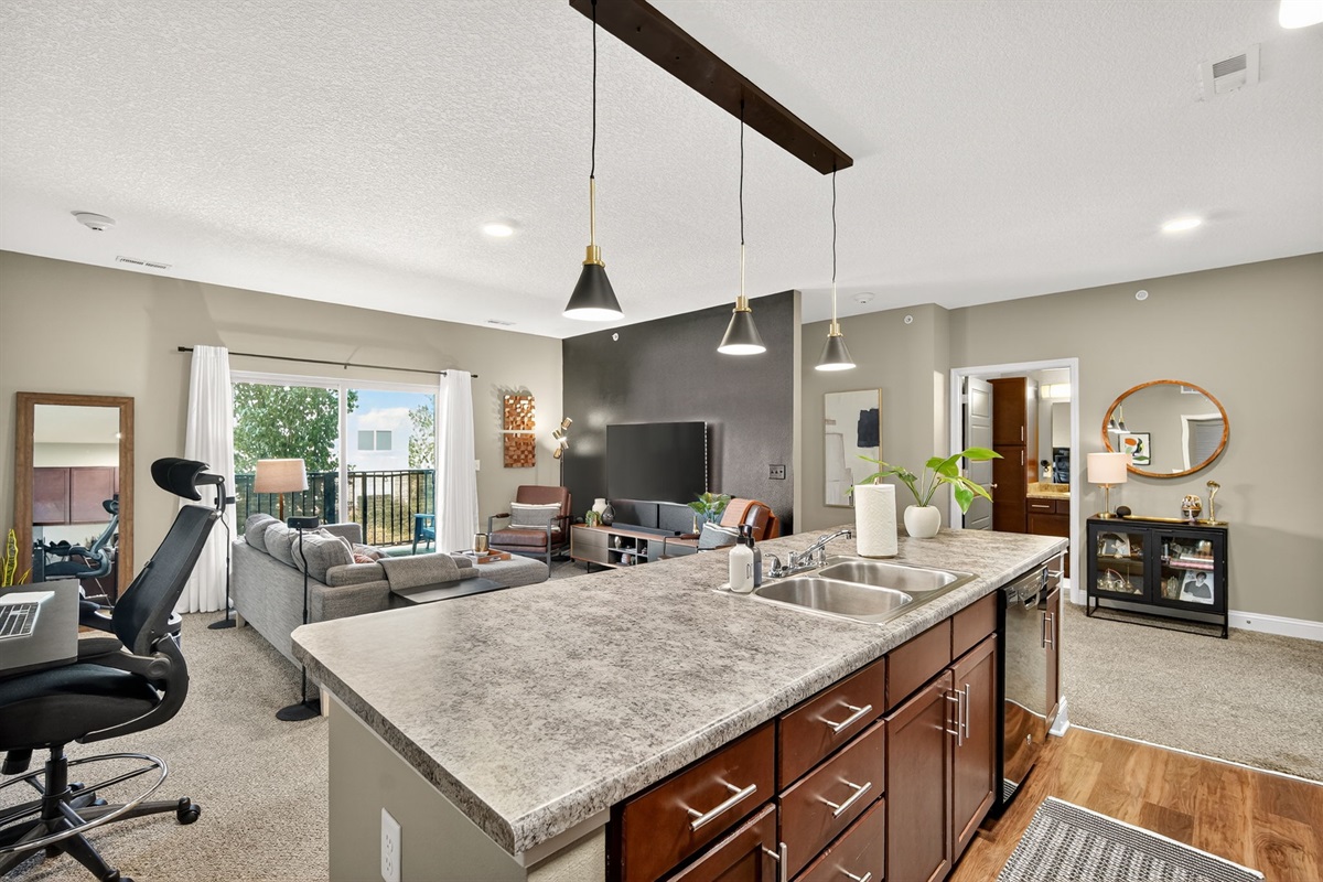 This open kitchen blends seamlessly with the living space, boasting rich cabinetry, sleek black appliances, and updated lighting.