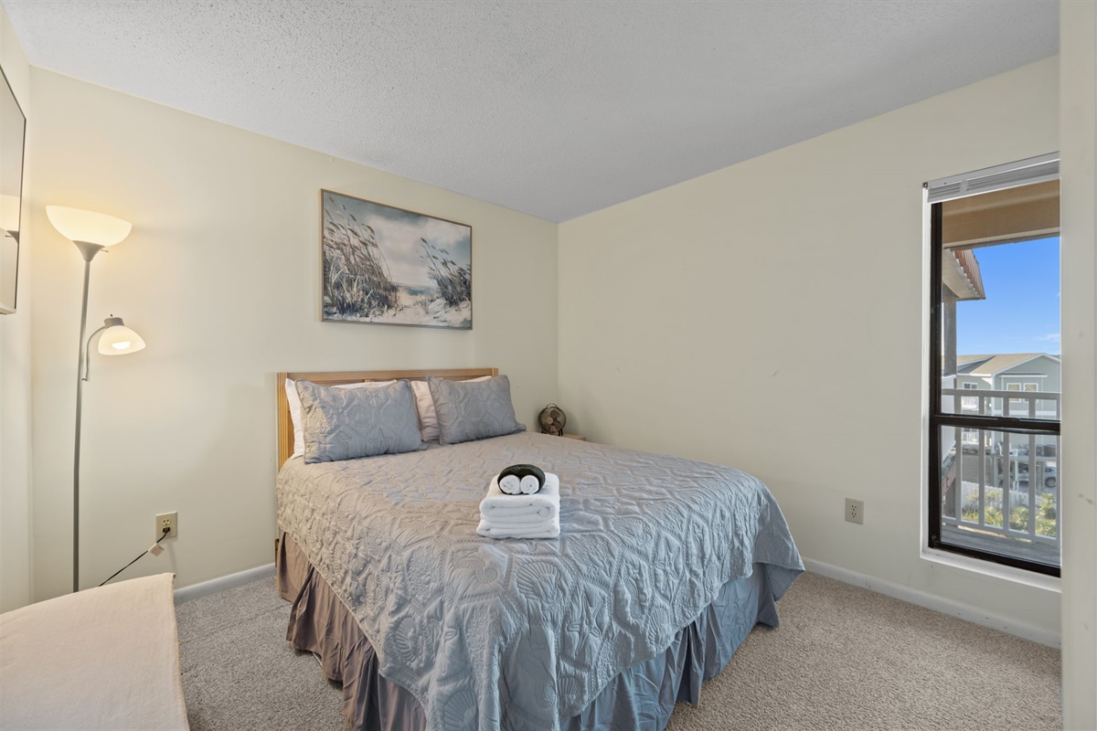 Peaceful bedroom retreat with cozy linens and a window view&mdash;perfect for unwinding after a sun-soaked beach day