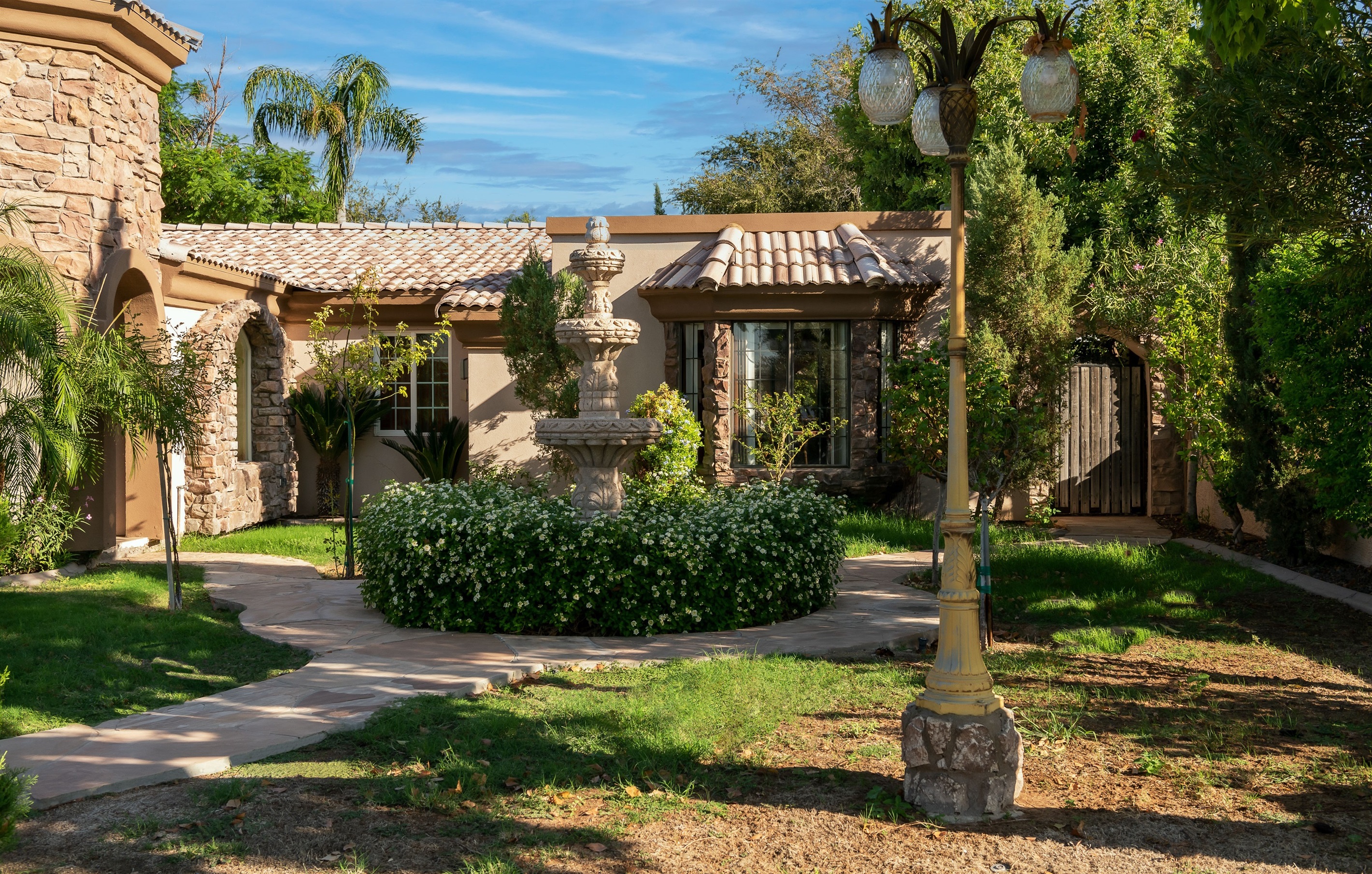 Lush landscaping and a sunlit courtyard welcome you to this elegant desert retreat with timeless architectural beauty.