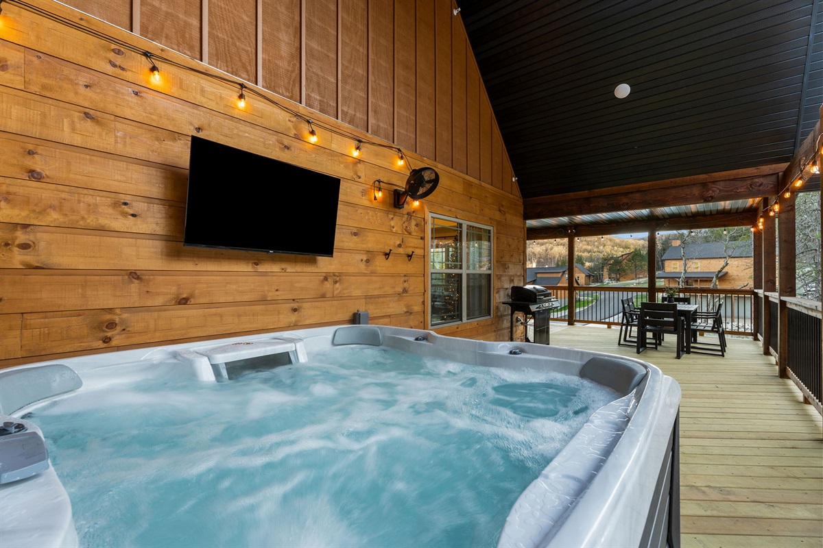 Hot tub on the covered deck with space to lounge nearby.