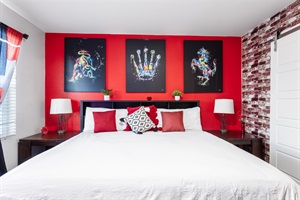 Master Bedroom: A serene retreat of comfort and style, featuring a luxurious king-sized bed, striking red accent walls, and captivating artwork that blends creativity with relaxation.