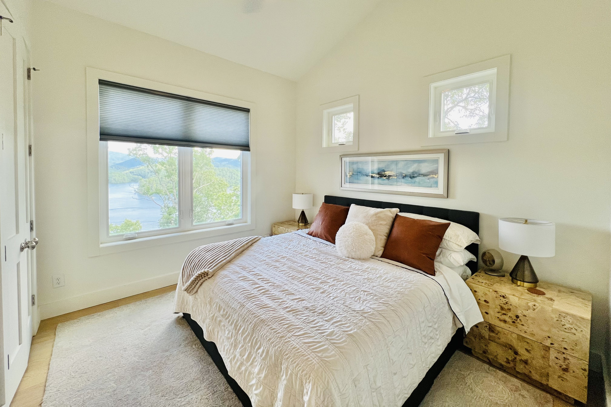 Wake up to lake views.
The main-level primary suite features a king bed, peaceful mountain and lake views, and a private ensuite bathroom with a spacious walk-in shower and double vanity.