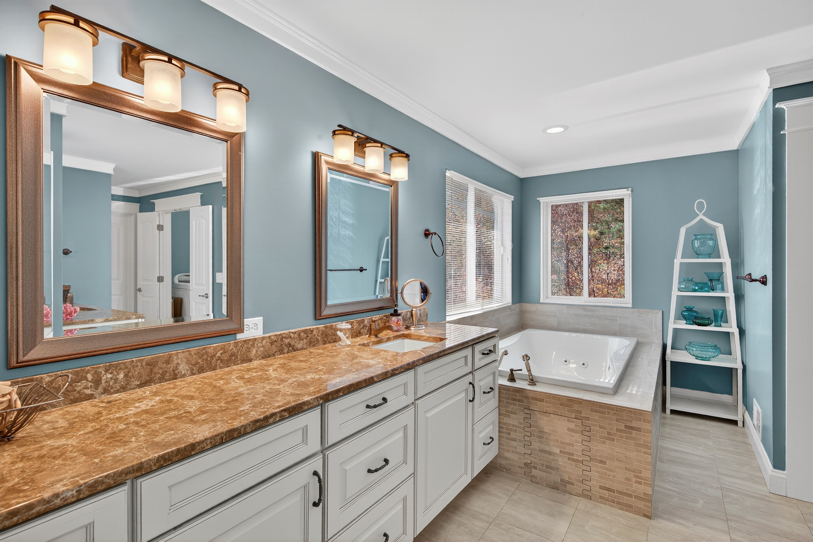 Luxurious ensuite bathroom with a deep jetted spa tub and wooded views.