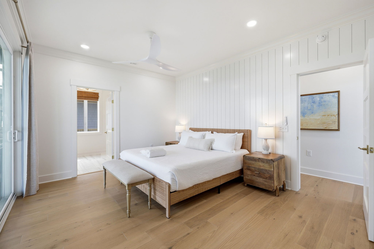 Bright first-floor master bedroom with shiplap accent wall, natural wood bed frame, and ensuite bathroom access