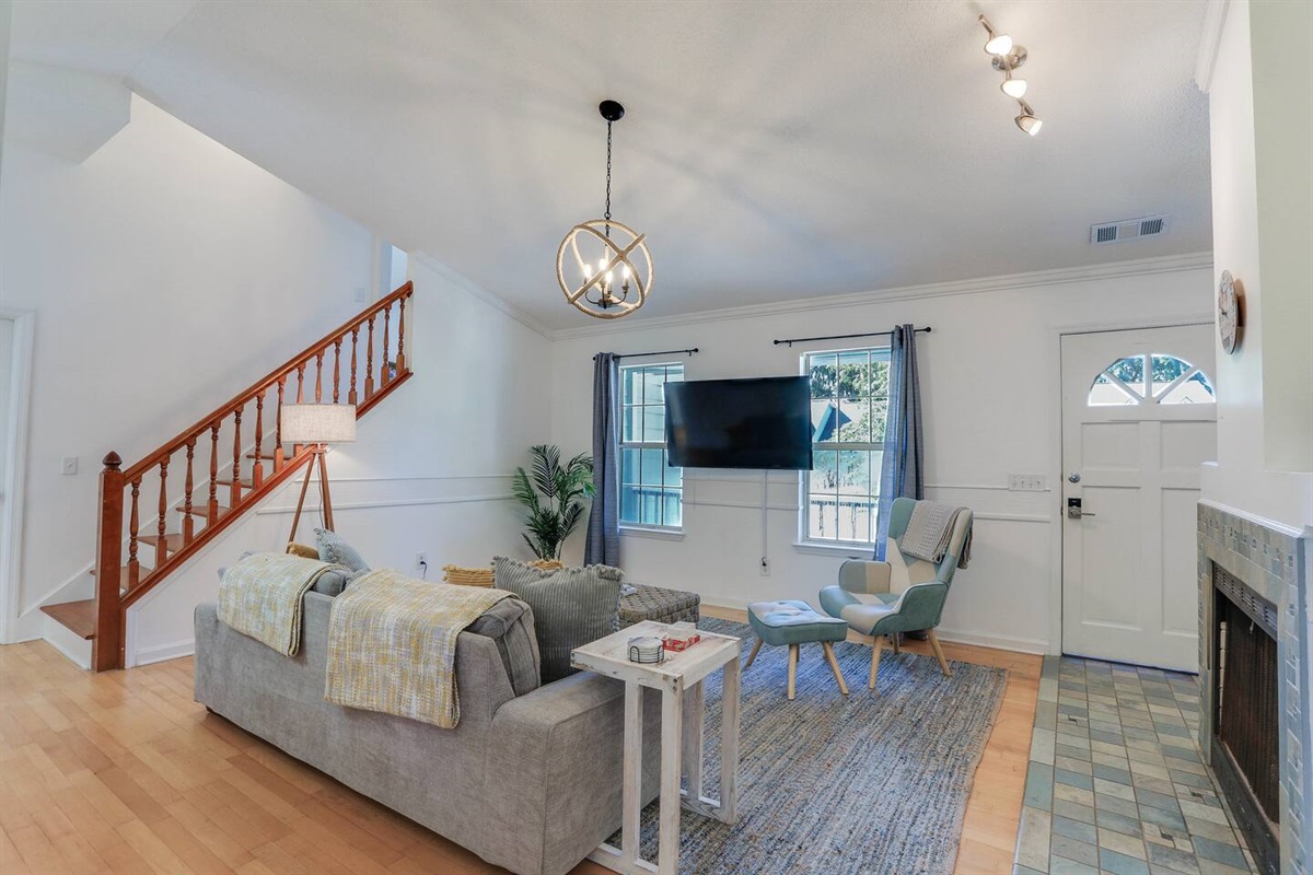 The living room at is bright and airy, with large open windows that let in plenty of natural light, high ceilings that create a spacious feel, and a smart TV for your entertainment needs.