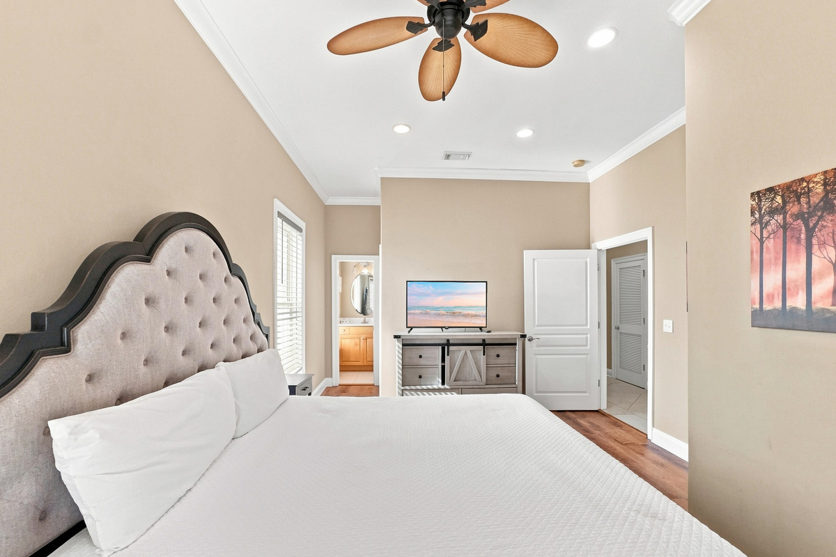 Bright bedroom with a tufted headboard and mounted smart TV