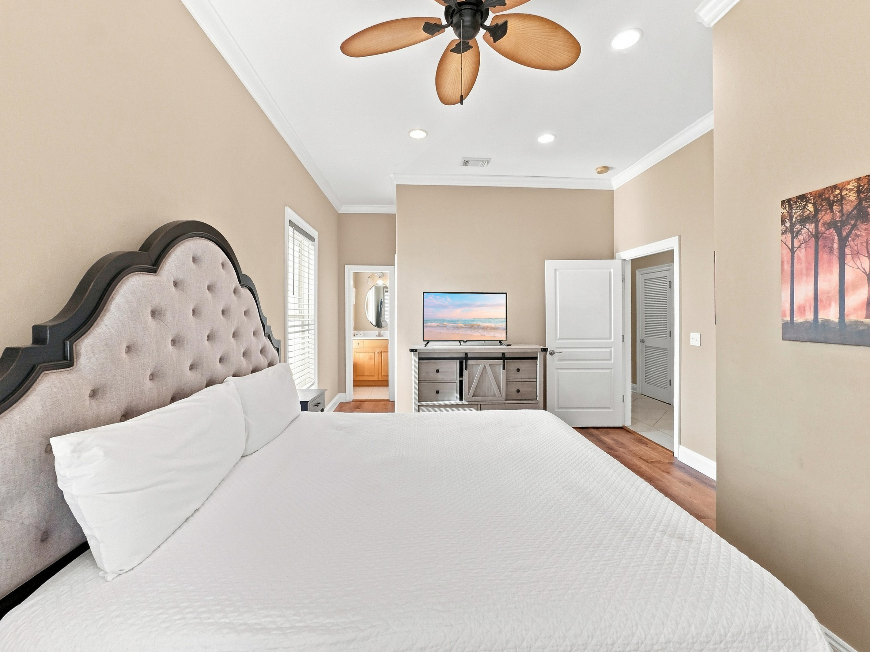 Bright bedroom with a tufted headboard and mounted smart TV