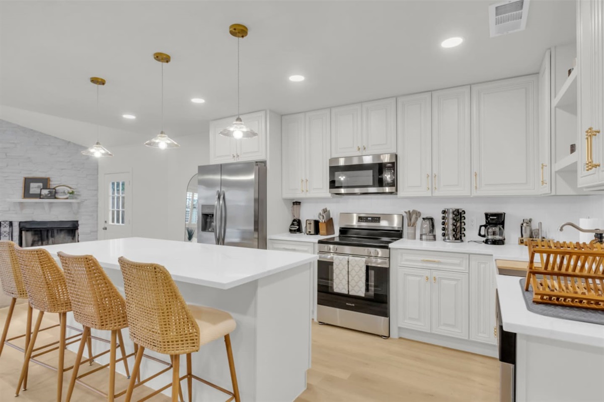 Bright kitchen with island seating for four, open shelving, dishwasher, microwave, and cooking basics. Perfect for guests who want a fully stocked setup while traveling.