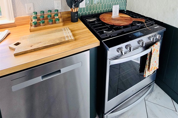 Ready to cook, bake, and gather—this kitchen features a sleek dishwasher, stainless range with microwave hood, and all the essentials: spices, utensils, and even a pizza peel for your next alfresco masterpiece.