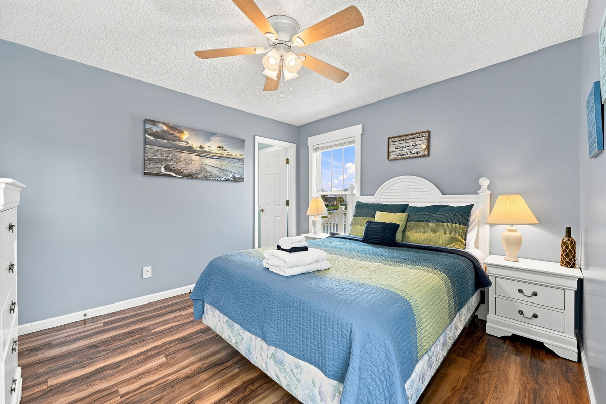 Unwind in the spacious primary suite featuring a comfortable queen bed, calming coastal d&eacute;cor, and a private ensuite bathroom