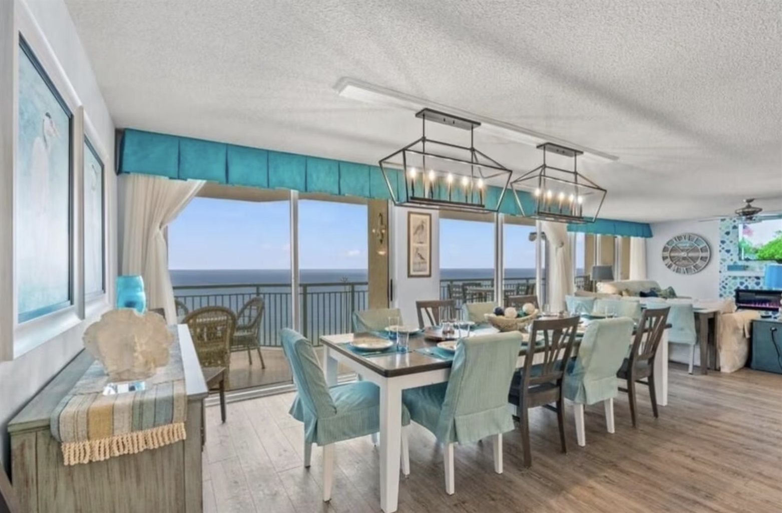 The large dining table in the open-concept living space seats a large family, and features a wall of sliding glass doors for incredible ocean views.