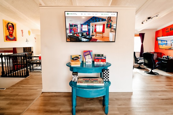 A cozy corner where a TV stands ready for streaming marathons, flanked by shelves stocked with board games.