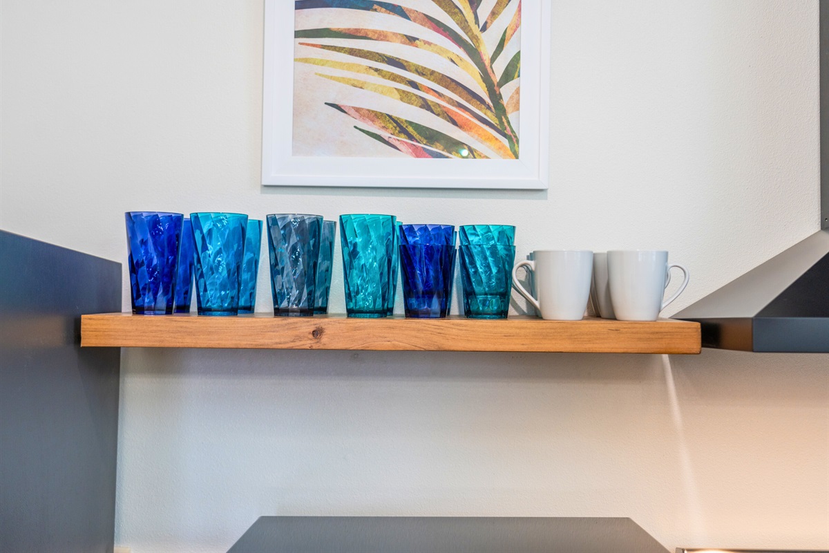 Bright and colorful glassware and mugs are neatly arranged, ready for refreshing drinks or your morning coffee.