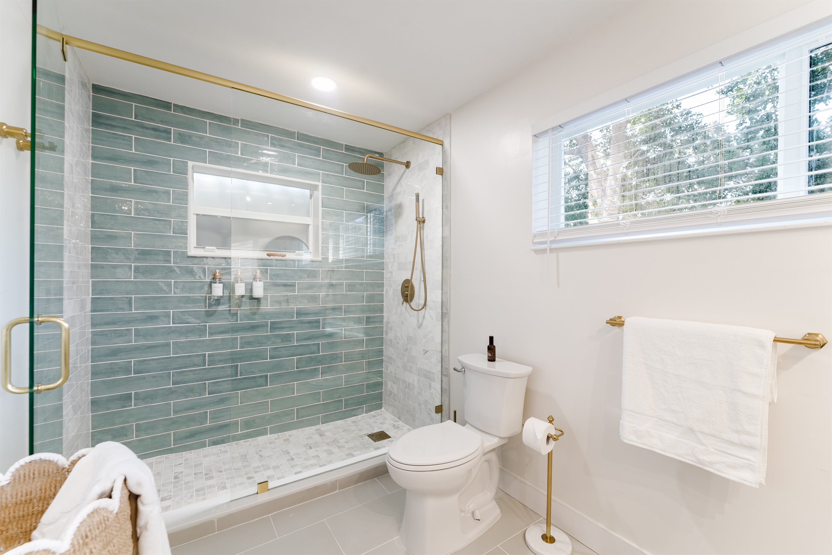 Spa-inspired ensuite with a walk-in glass shower, soft sage tile, and brushed brass fixtures. A double vanity with designer mirrors creates a bright, hotel-style retreat made for slow mornings and effortless luxury.