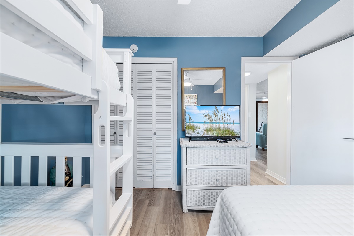 This charming guest room with queen-size bed and bunk bed features a well-crafted design with attention to detail. The warm tones and comfortable furnishings create a welcoming and relaxing environment.