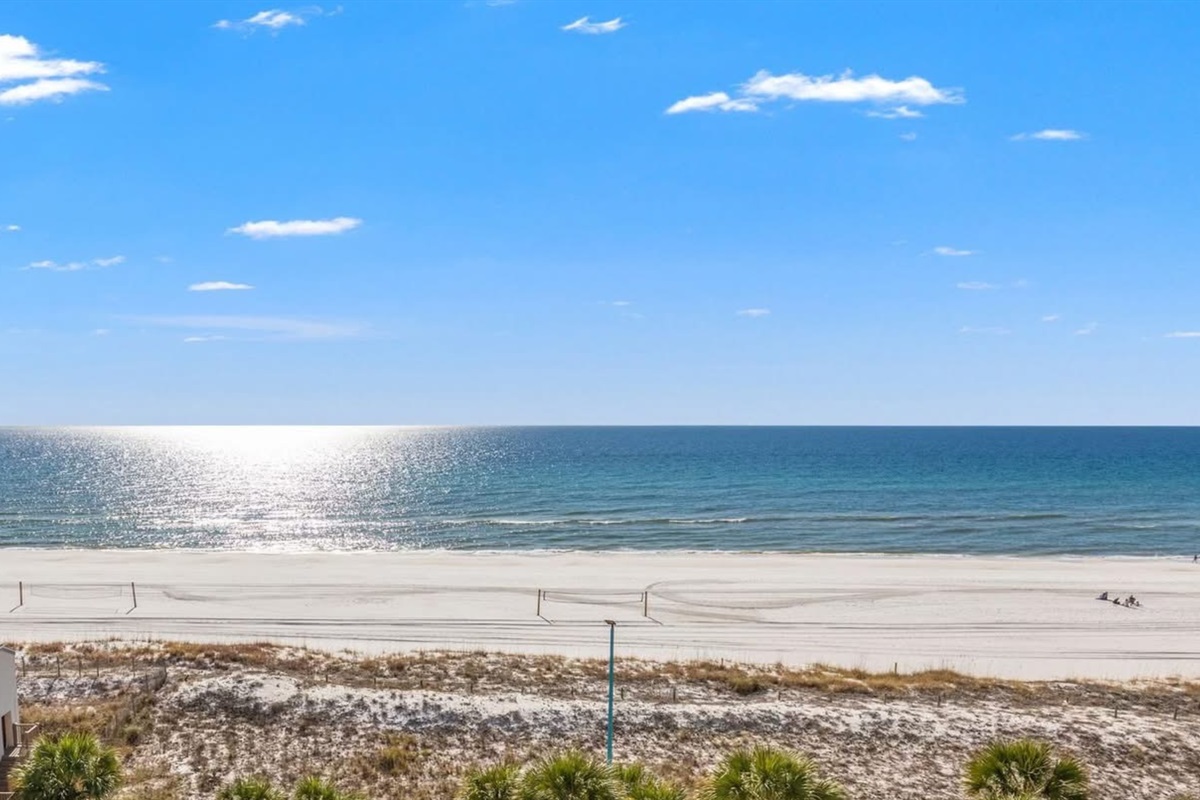Private balcony with expansive, unobstructed Gulf views — your front-row seat to the emerald water and sugar-white sand.