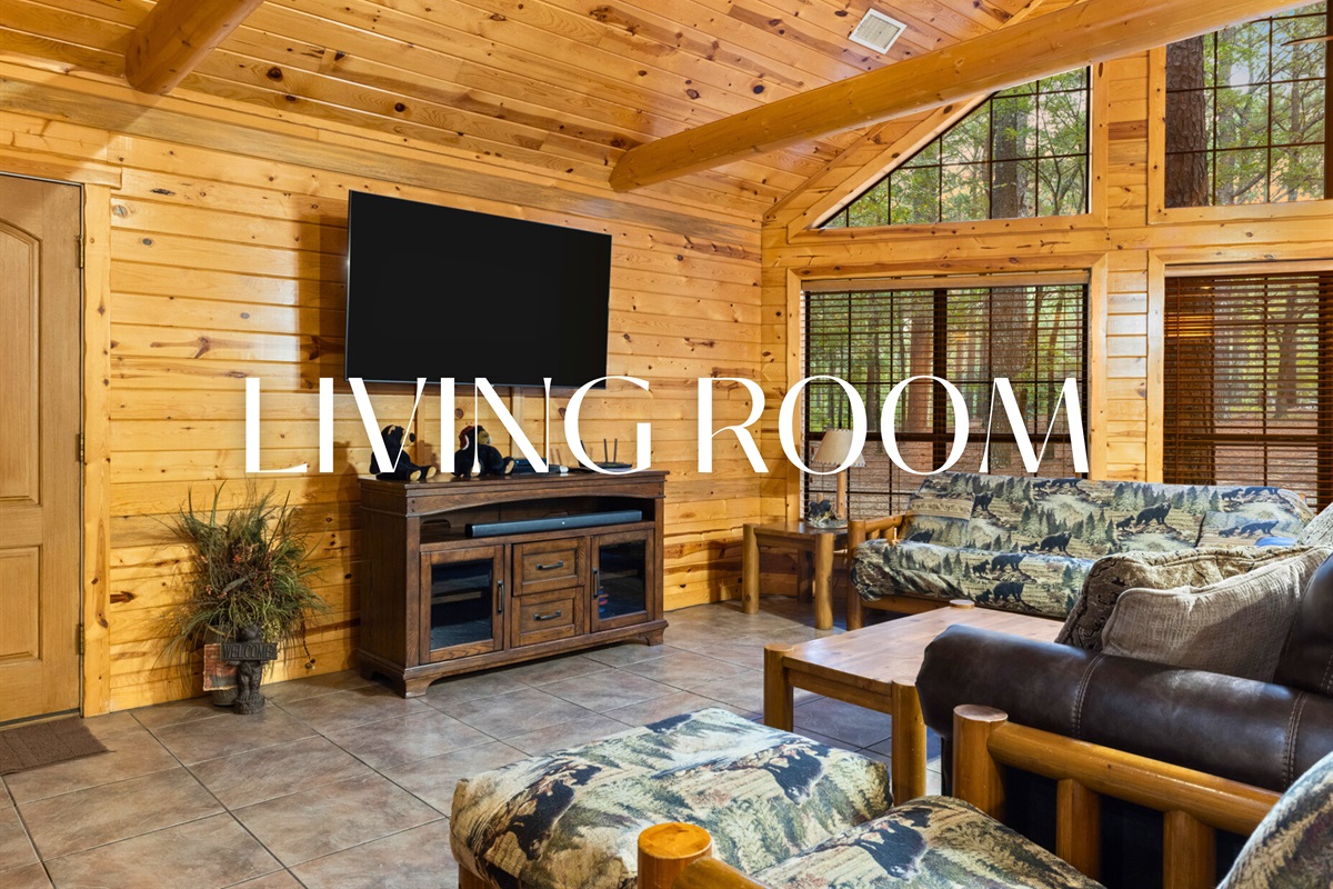 Living room with vaulted ceilings, big screen TV, and forest views