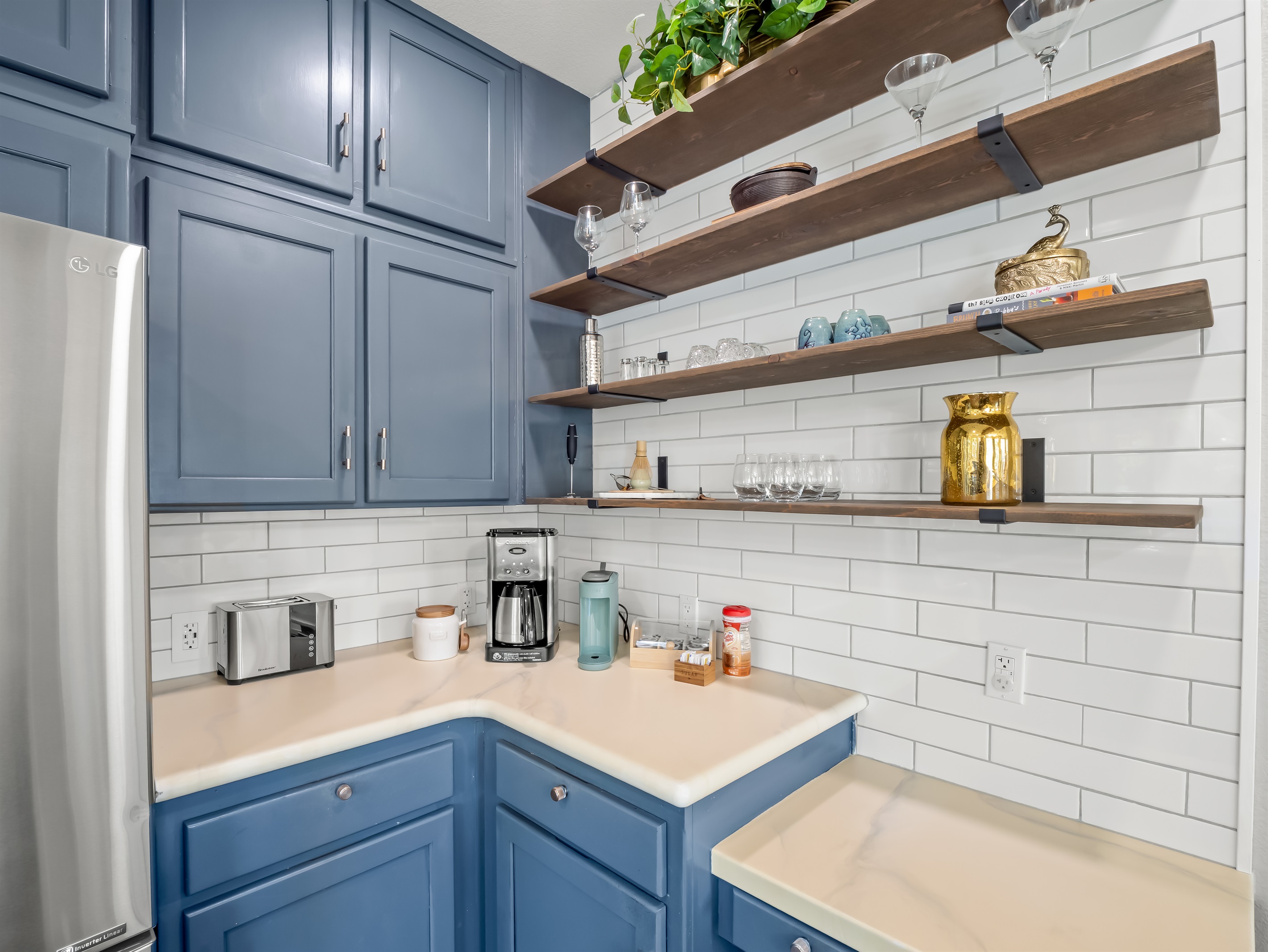 Fully stocked coffee station with drip coffee maker, toaster, electric kettle, mugs, wine glasses, and open shelving for easy access—everything you need for relaxed mornings at home.