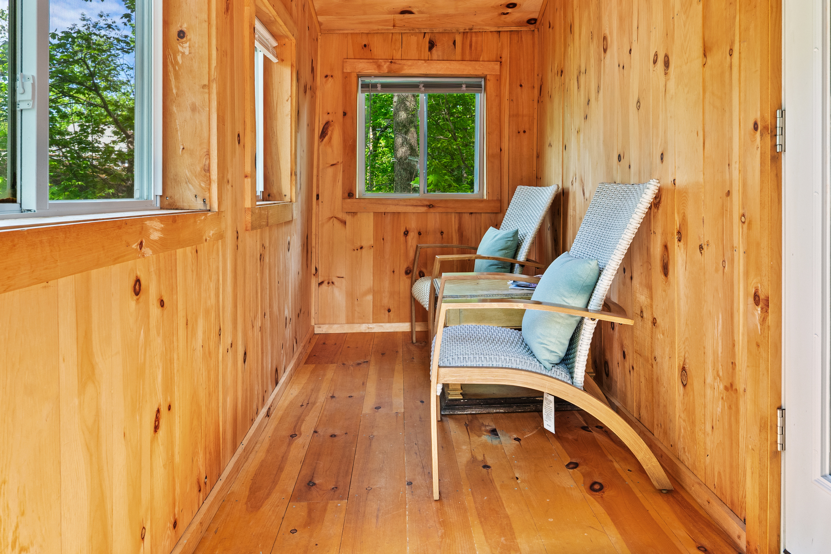 Inside the Pine Breeze Room. Open the screened windows to let in fresh island air. Features seating for two, easy deck access, and a pet-friendly layout. It’s the perfect bug-free sanctuary for morning coffee or relaxing after a hike.