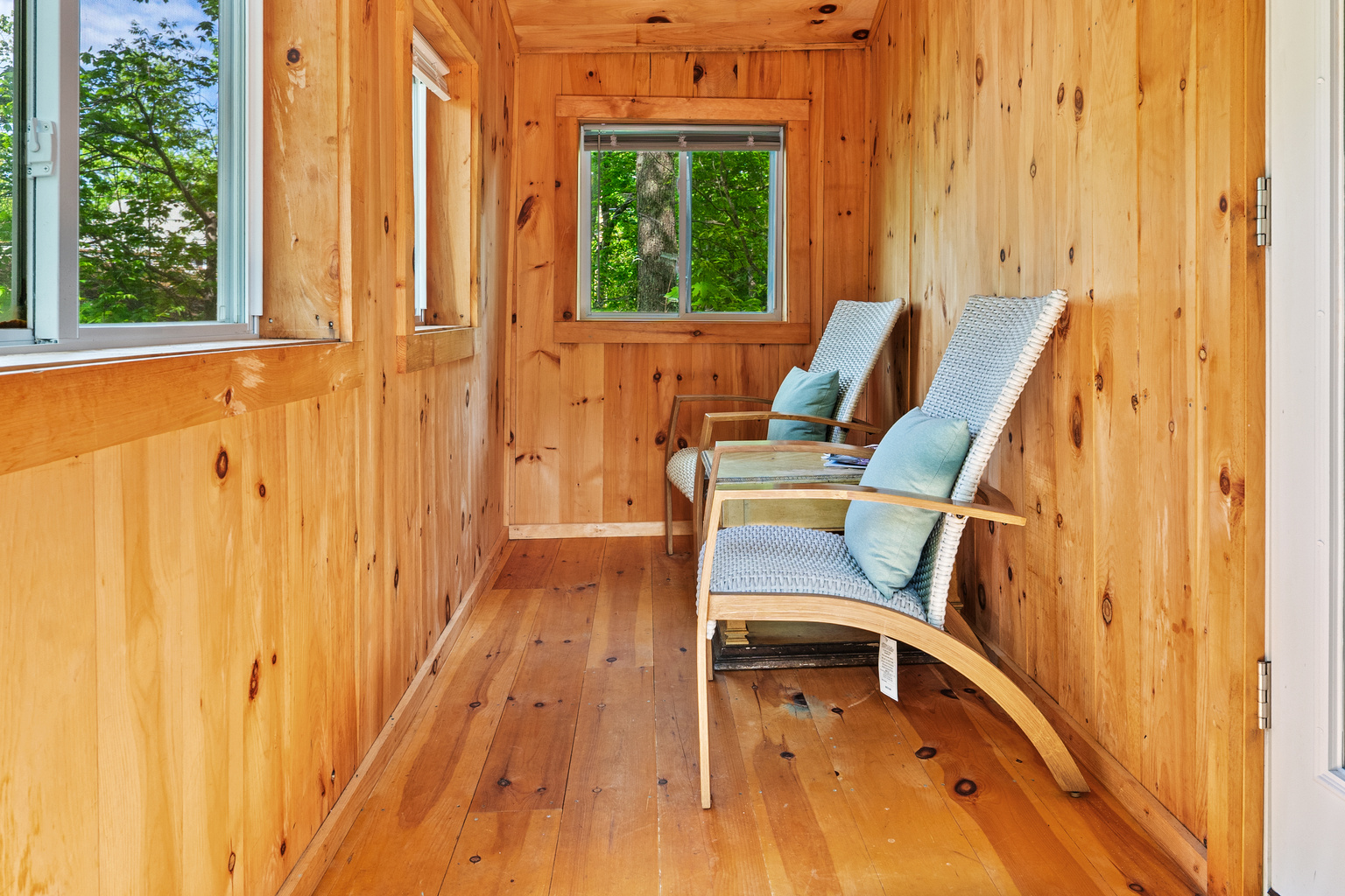 Inside the Pine Breeze Room. Open the screened windows to let in fresh island air. Features seating for two, easy deck access, and a pet-friendly layout. It’s the perfect bug-free sanctuary for morning coffee or relaxing after a hike.
