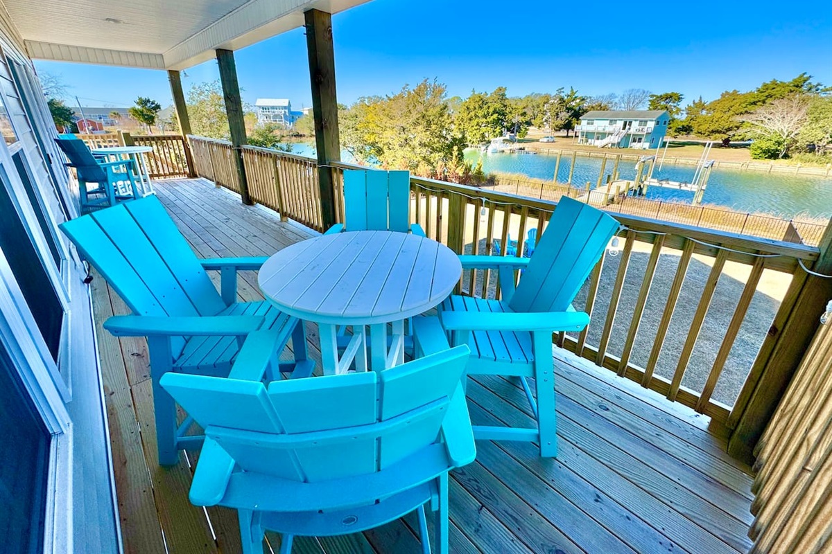 Private backyard dock with boat lift and fillet table, fenced-in backyard, fire pit with Adirondack chairs, hammocks, propane grill, picnic table, outdoor shower, expansive waterfront back deck with string lights, neighborhood boat ramp