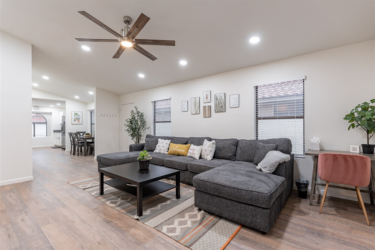 Comfortable couch in the living room with writing desk, and is open to dining room and kitchen.