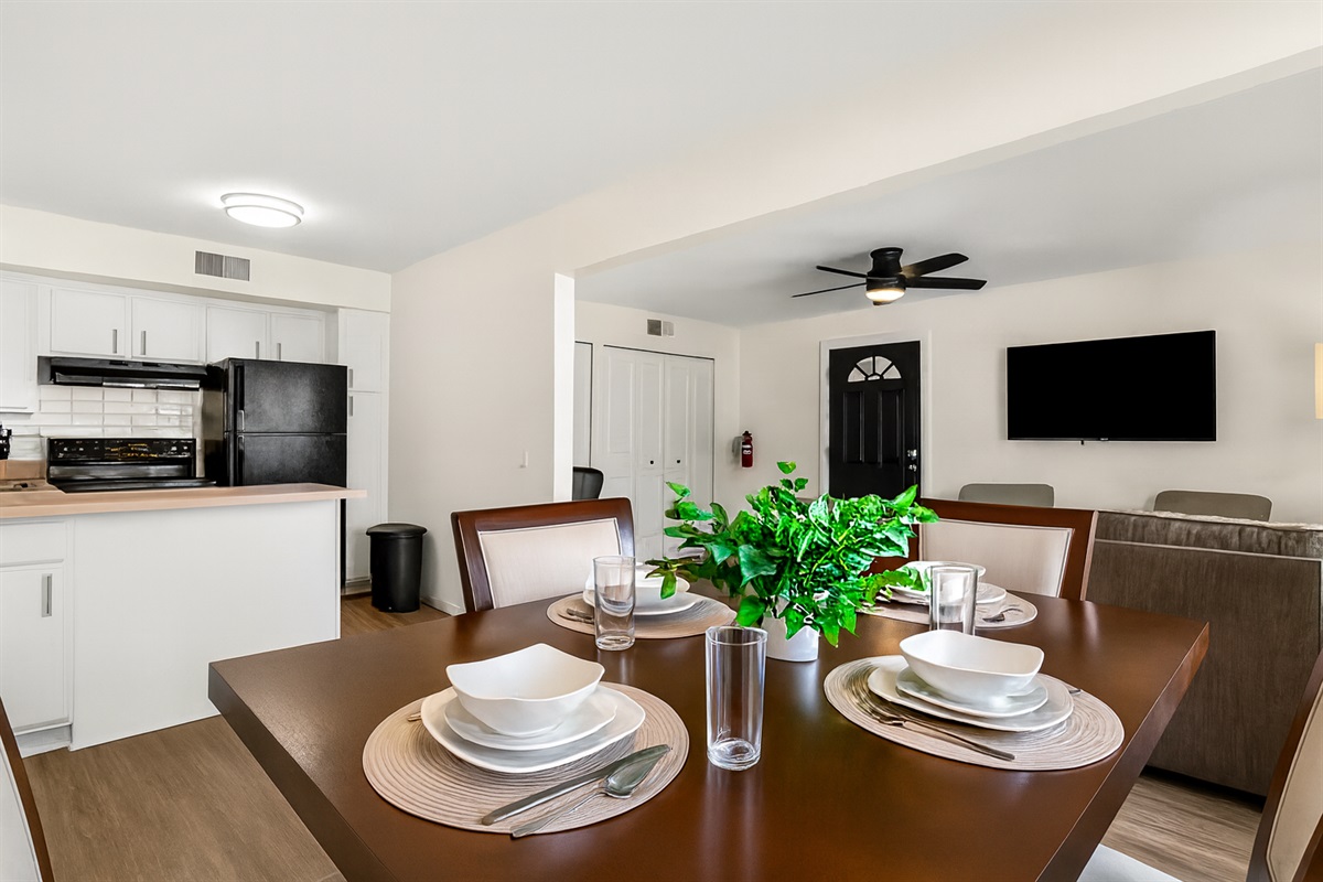 Bright open-concept dining and living space featuring a modern kitchen, cozy seating area with TV, and a stylish dining table setup—perfect for gathering and entertaining.