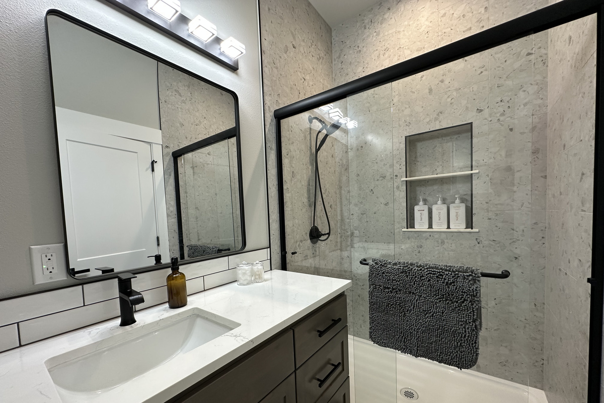 A full bath on the lower level with a walk-in shower, stocked niche, quartz counter and matte black fixtures.