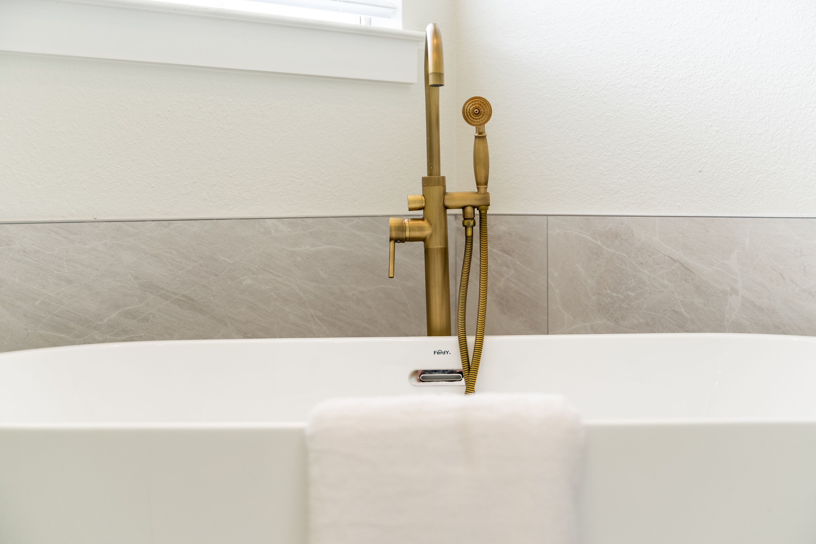 Freestanding soaking tub paired with a gold floor-mount faucet — pure relaxation.