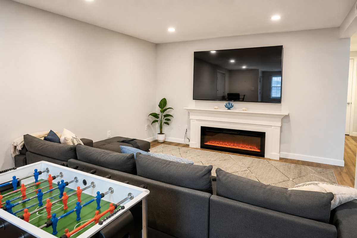 Basement living room with sectional, large smart TV, and electric fireplace